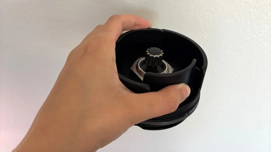 A hand holding the black Vitamix Nano blade base upside down to show the drive spine.