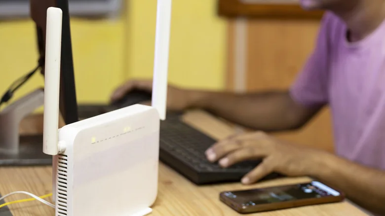 Wi-Fi router on desk alongside keyboard and smartphone.
