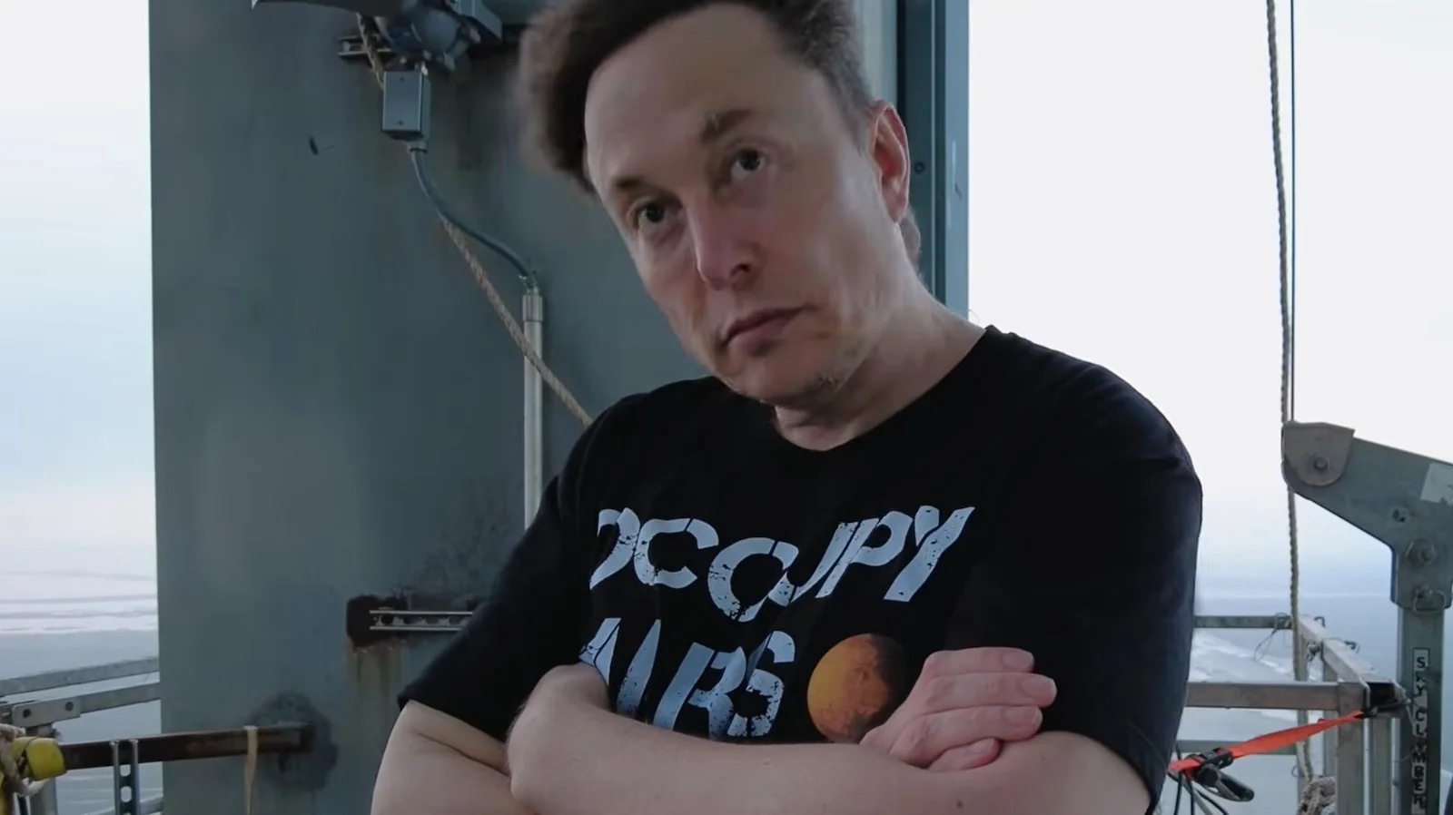 Elon Musk folding his arms.
