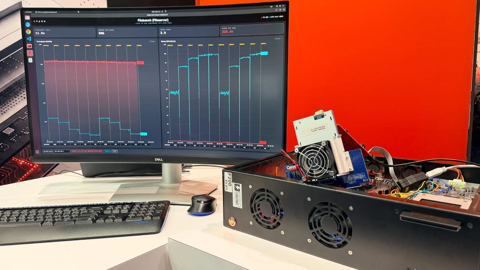 A curved monitor at FADU’s OCP Global Summit booth shows a Filebench dashboard comparing a live FS-SSD run with a recorded NFS-over-RDMA run, beside an open test chassis with an SSD mounted on a riser