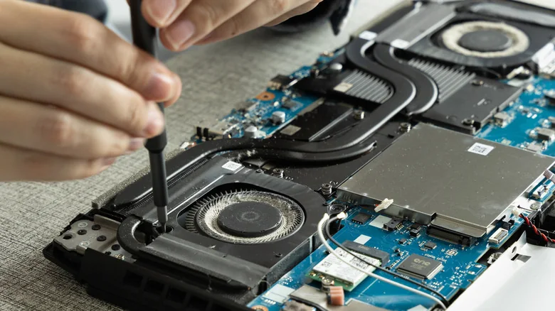 An open laptop with two cooling fans, heat pipes and the motherboard exposed.