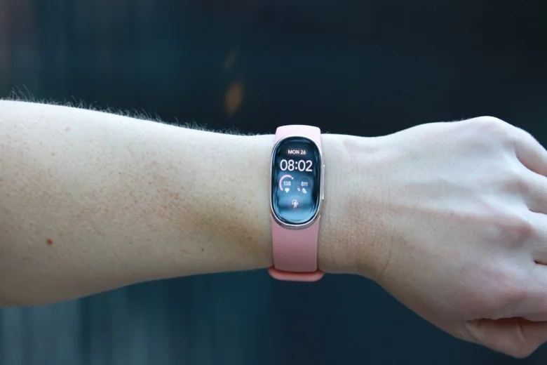 A Fitbit Edge with pink silicone band on a person's wrist.