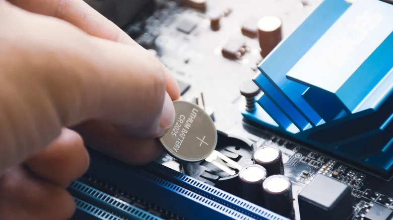Hand installing a new CMOS battery into a PC.