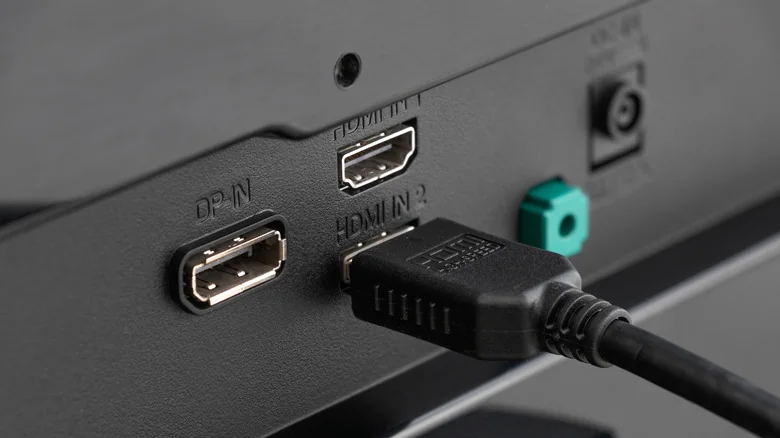 HDMI cable connected to an HDMI input on the back of a display, alongside other ports.