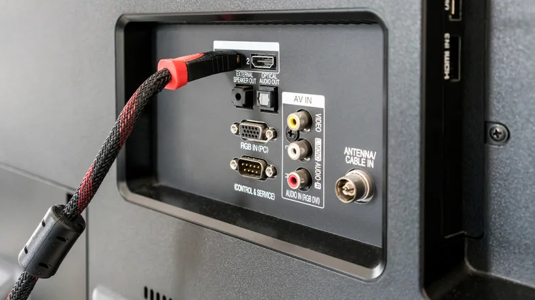 An HDMI cable, plugged into the back of a TV amongst various other ports.