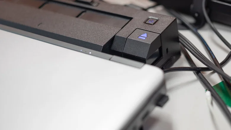 A docking station beside a laptop with several connected cables.