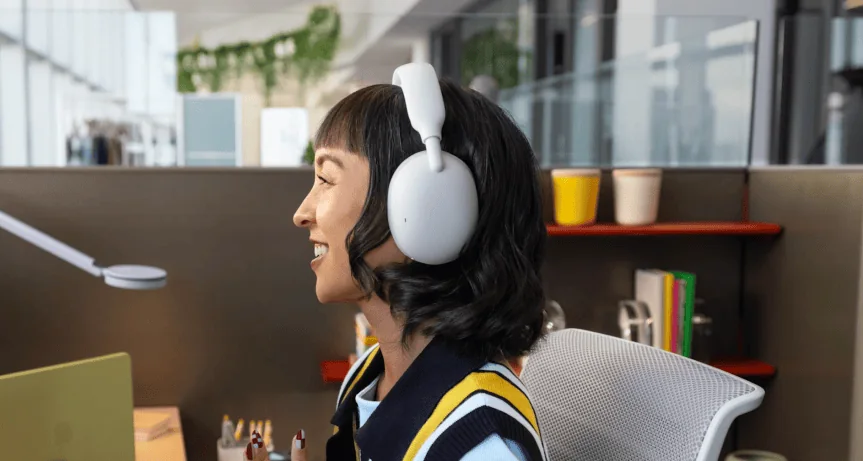 Office worker shown wearing the Logitech Zone Vibe Pro in an open office environment.