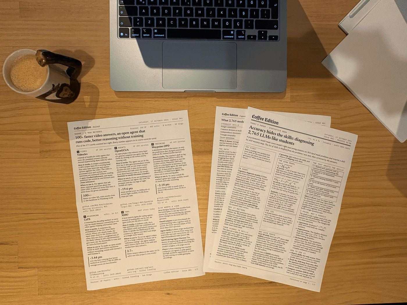 Printed Coffee Edition pages on a desk next to a cup of coffee: issue 001 and its page of new AI methods