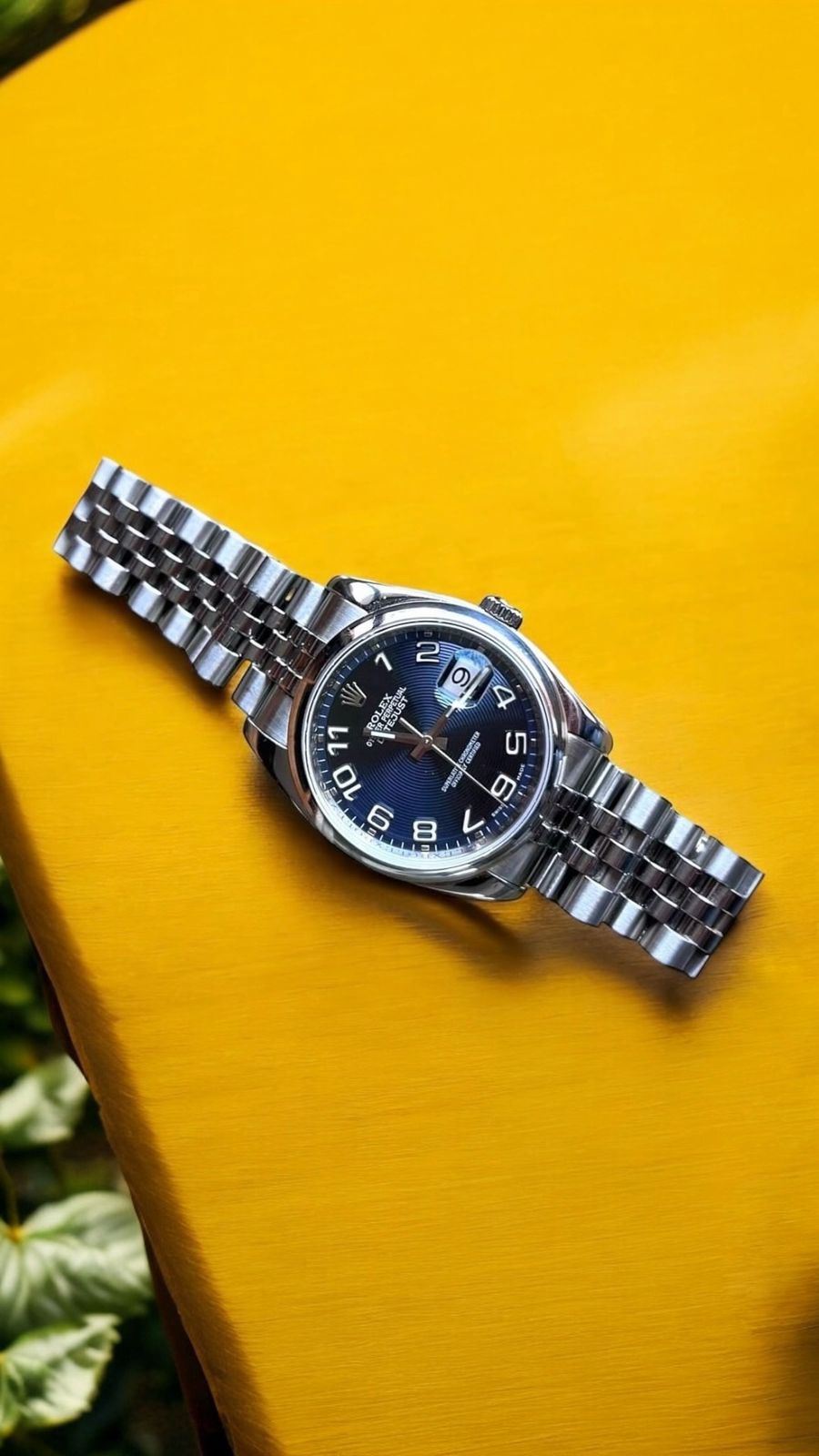 Rolex Datejust con esfera azul sobre una superficie amarilla