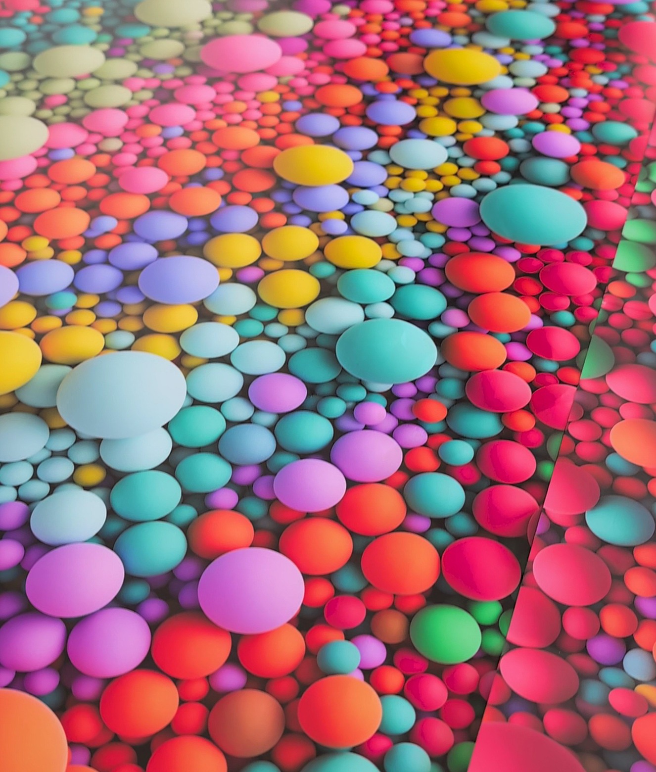 The same bubbles test file printed twice, the two prints meeting at a seam in one frame at the factory: left of the seam the spheres are matte with deep, rounded shading; the sheet to the right is glossier and flatter