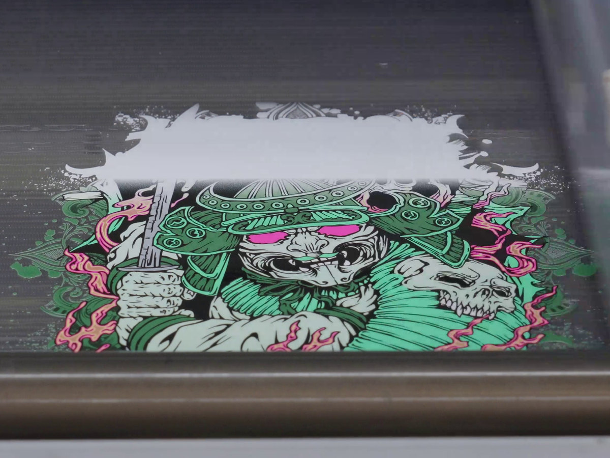 A bold illustrated print building on dark media under the HB18UV PRO's head, the white going down ahead of the colour