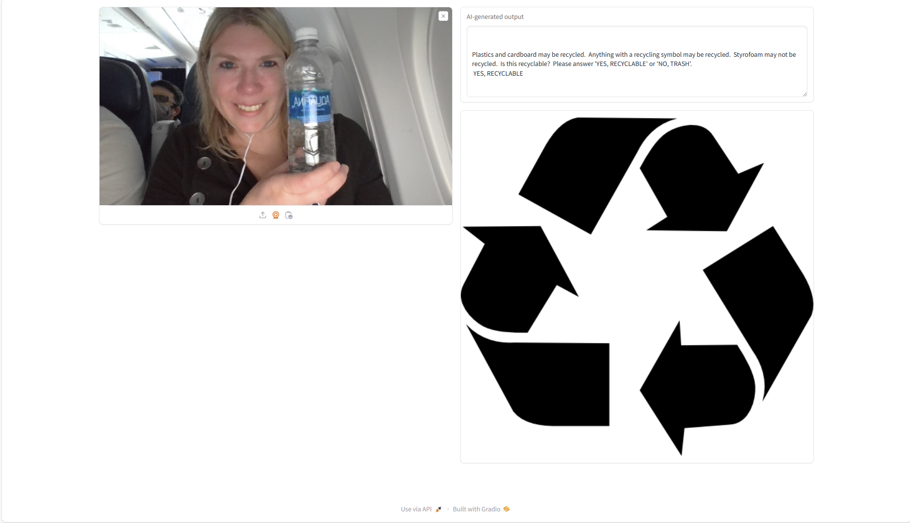 "The input to the model is an image of a woman on an airplane holding a plastic water bottle.  The output displayed is a large recycling symbol."