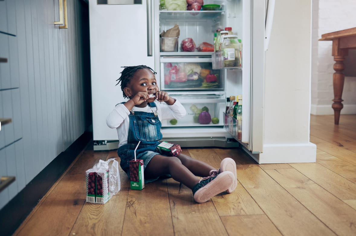 Girl sitting on the floor in front of an open refrigerator