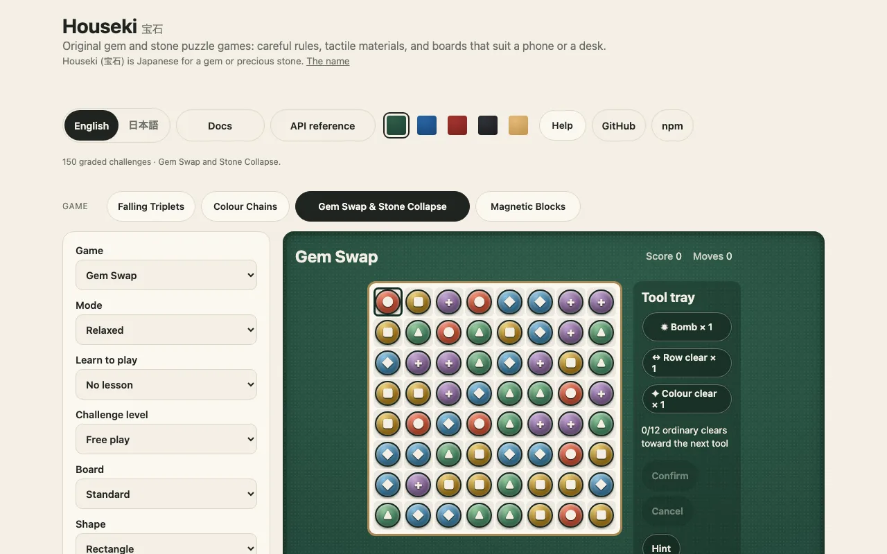 The demo on a desk, in English: the page header with its language chooser, the Docs and API reference links, five cloth patches and the Help switch, the page chooser (Falling Triplets, Colour Chains, Gem Swap and Stone Collapse chosen, Magnetic Blocks), the settings column, and Gem Swap on green felt: an eight by eight board of red, blue, green, gold and purple gems with a permanent symbol on each, and the tool tray beside it with Bomb, Row clear and Colour clear