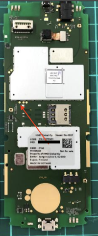 Mainboard of a TA-1307 Nokia 6300 4G, with the red arrow pointing to three gold contacts in the middle of the board, those being the UART testpoints in the order of TX, RX and ground