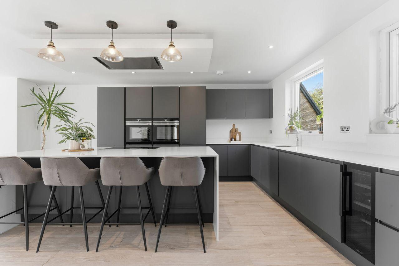 Otters Way, Hampton Water — kitchen with matt graphite cabinetry, white quartz island and integrated ovens