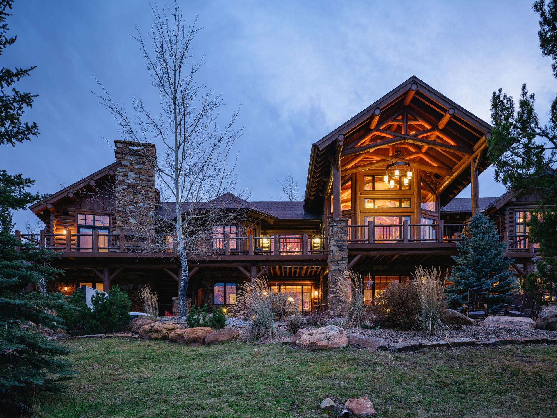 The timber-frame and stone elevations of 168 Charlie Russell Loop lit at twilight