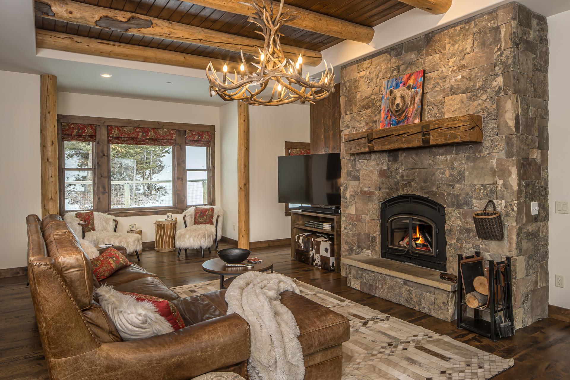 Stone fireplace with a reclaimed timber mantel beneath exposed log beams in the great room at 172 Ciel Drive
