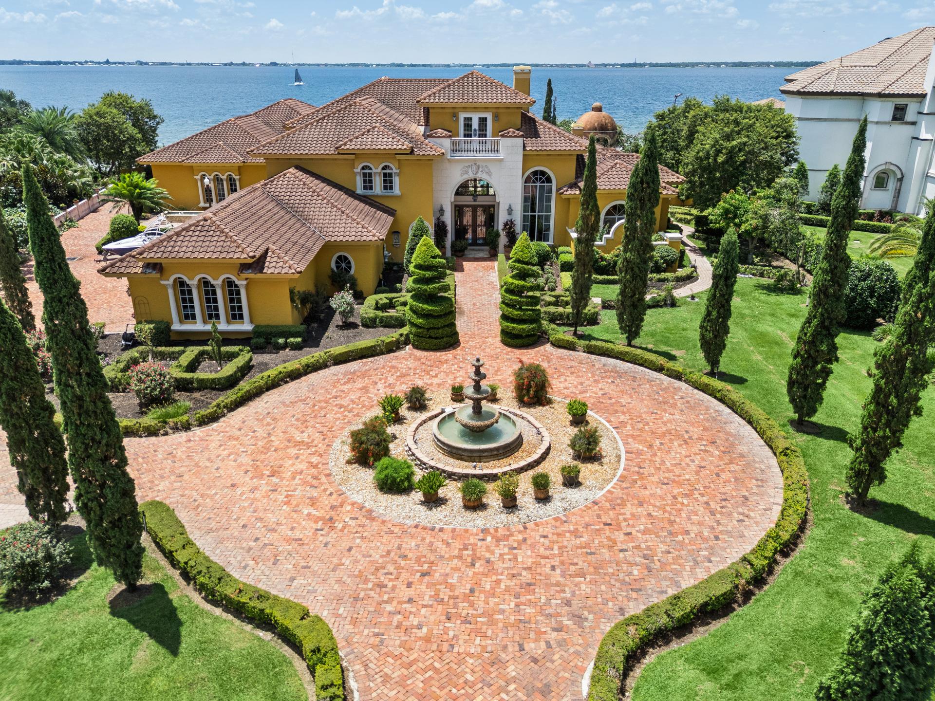 2961 Lakeview Dr, a Mediterranean lakefront estate in Sebring, Florida, seen from the air above its hand-laid Chicago brick motor court, tiered fountain and Italian-inspired gardens, with Lake Jackson beyond