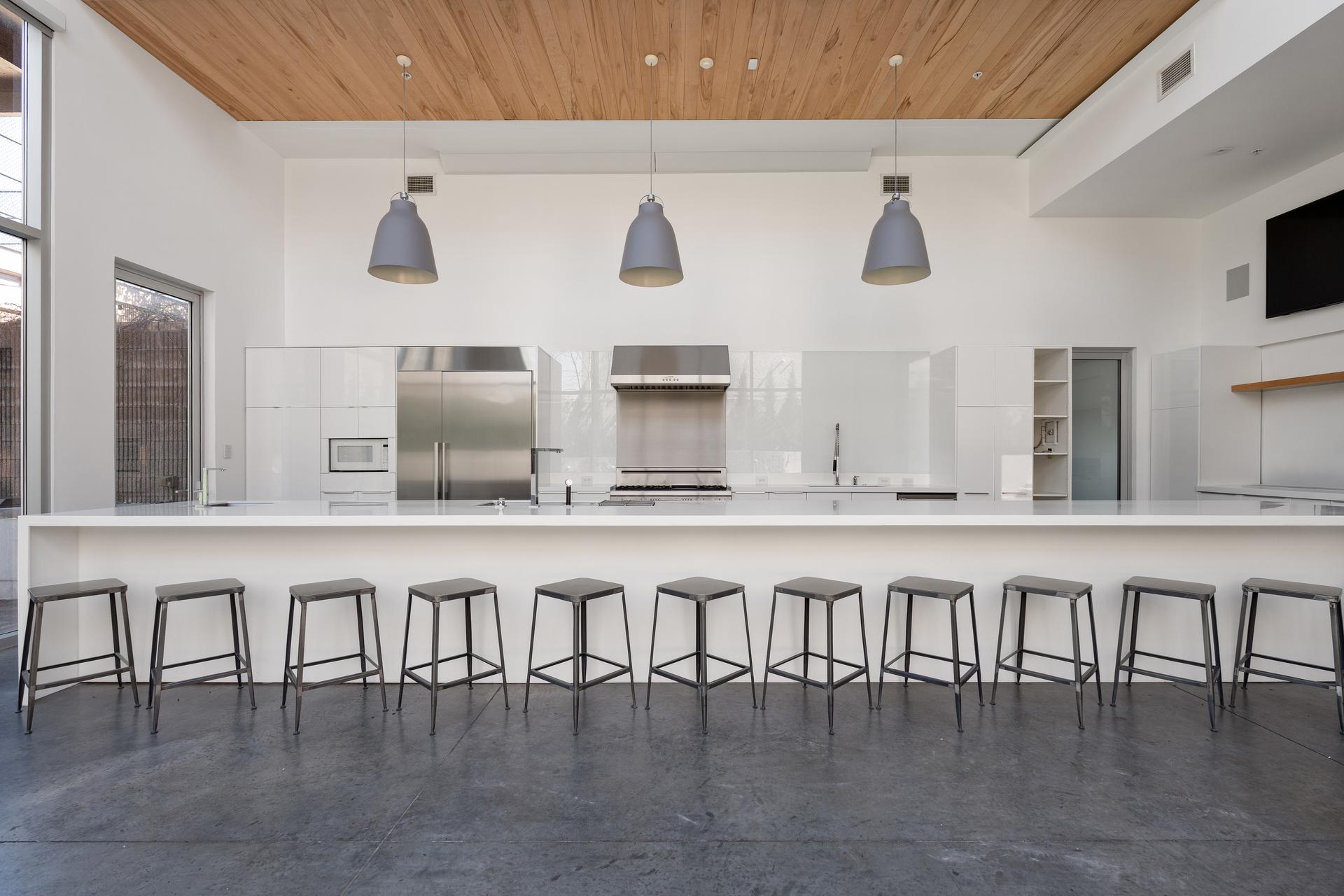 The chef's kitchen at 312 Madison Street, a long island with stools beneath a wood-clad ceiling and pendant lighting