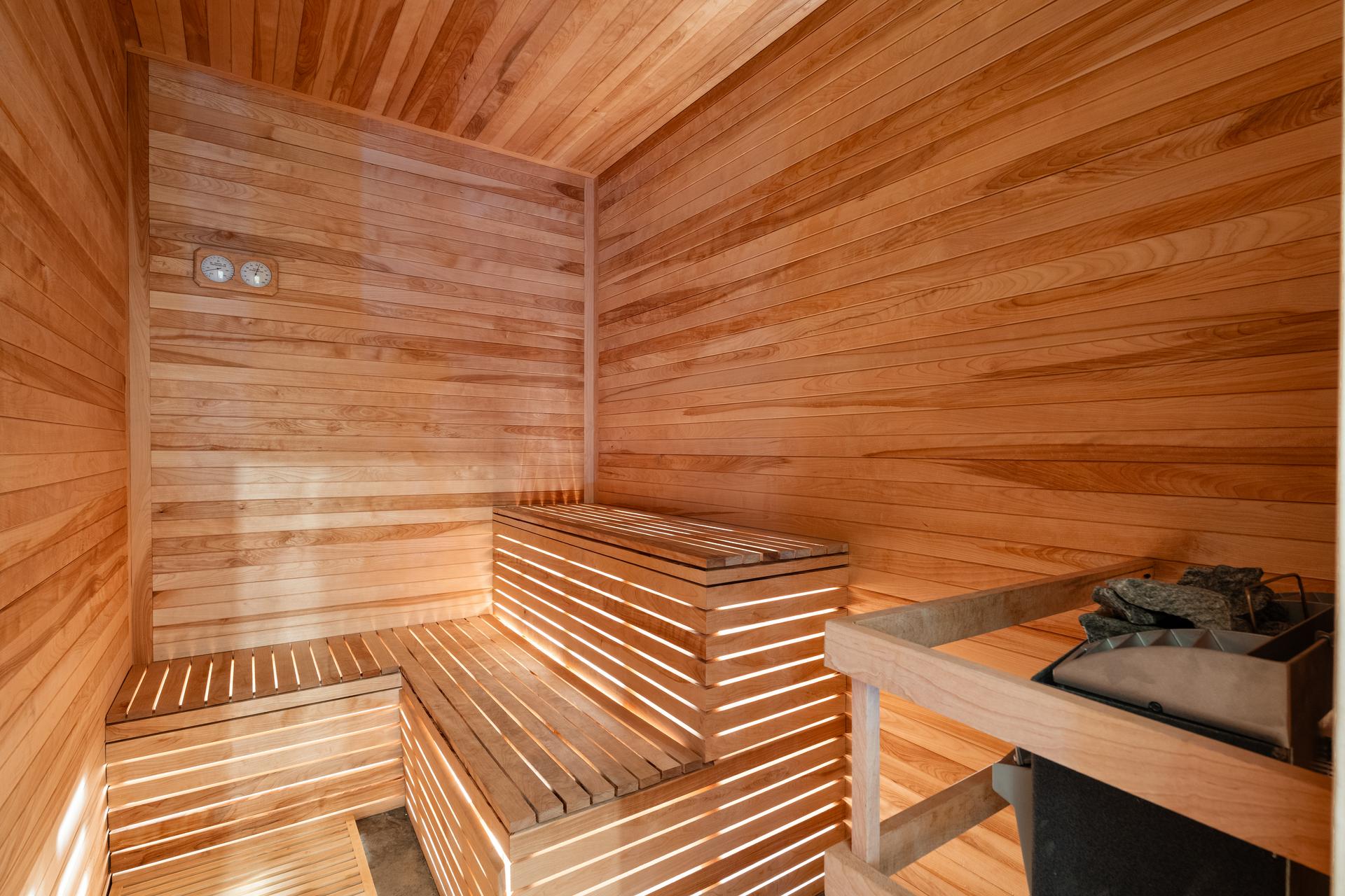 The cedar sauna at 312 Madison Street, with backlit slatted benches and a stone heater
