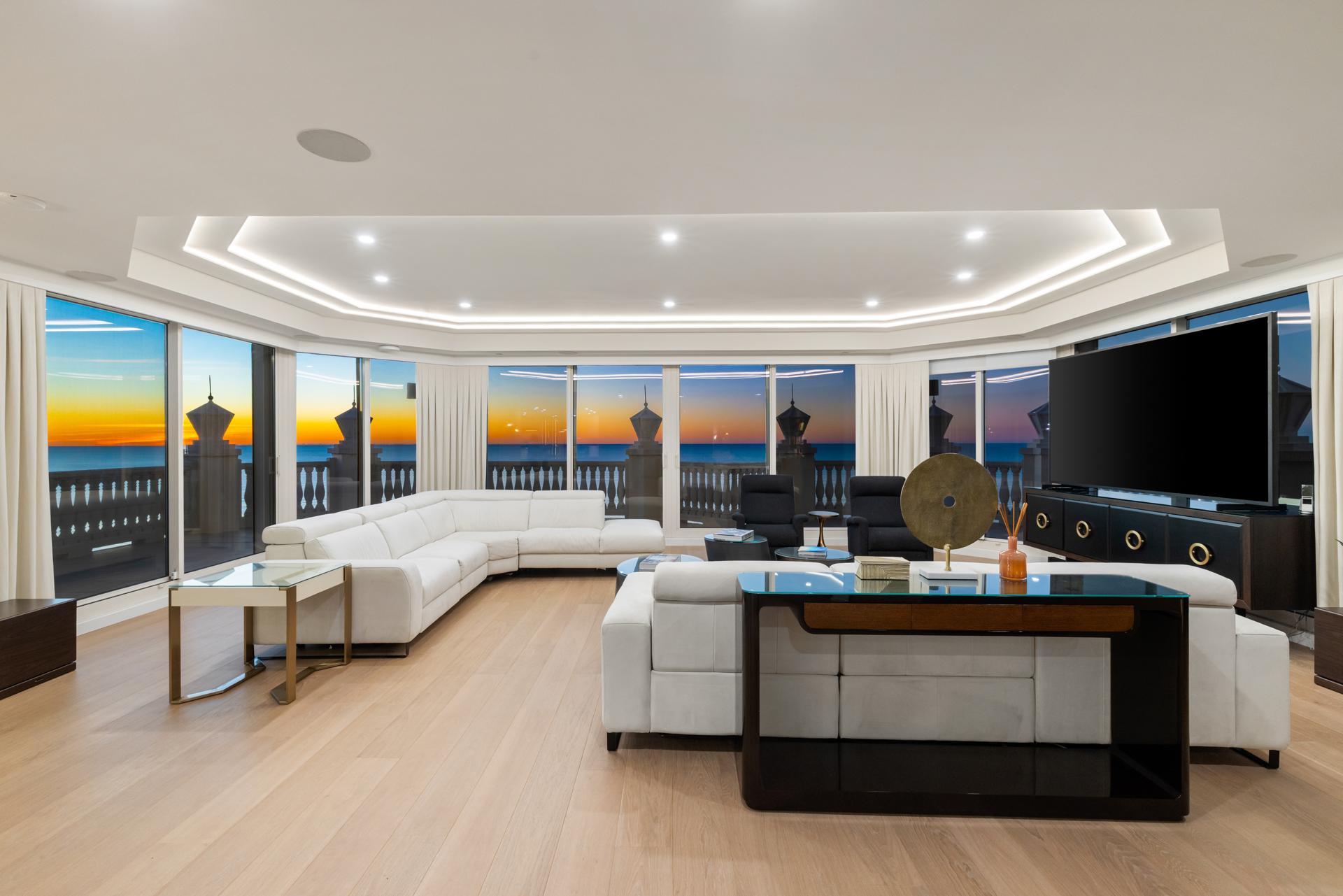 The Grand Salon at 4021 Gulf Shore Blvd N #11, its floor-to-ceiling glass open to the terrace and the Gulf at sunset