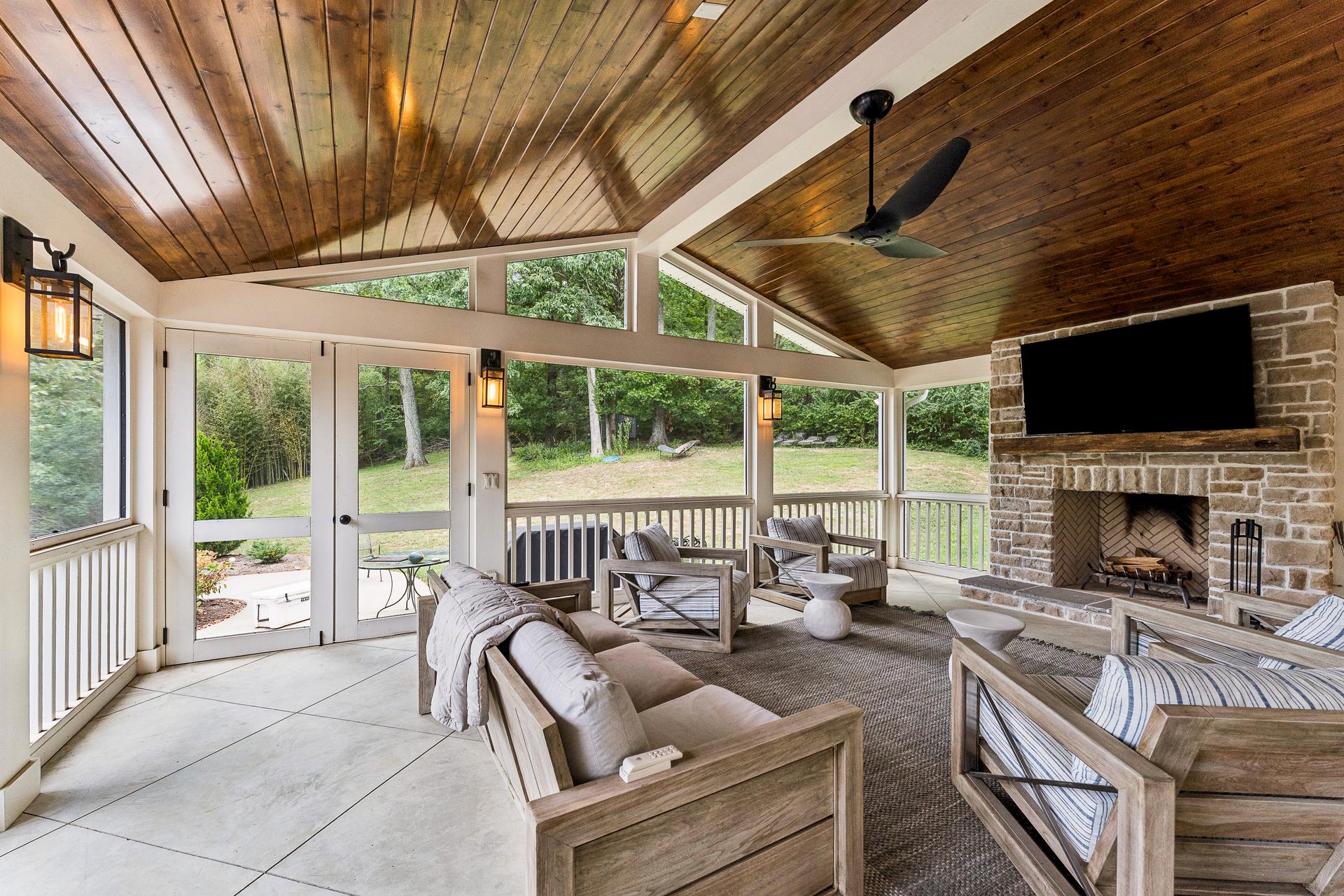 The screened porch at 805 Cammack Court, with a stone fireplace and wood ceiling overlooking the park-like rear lawn