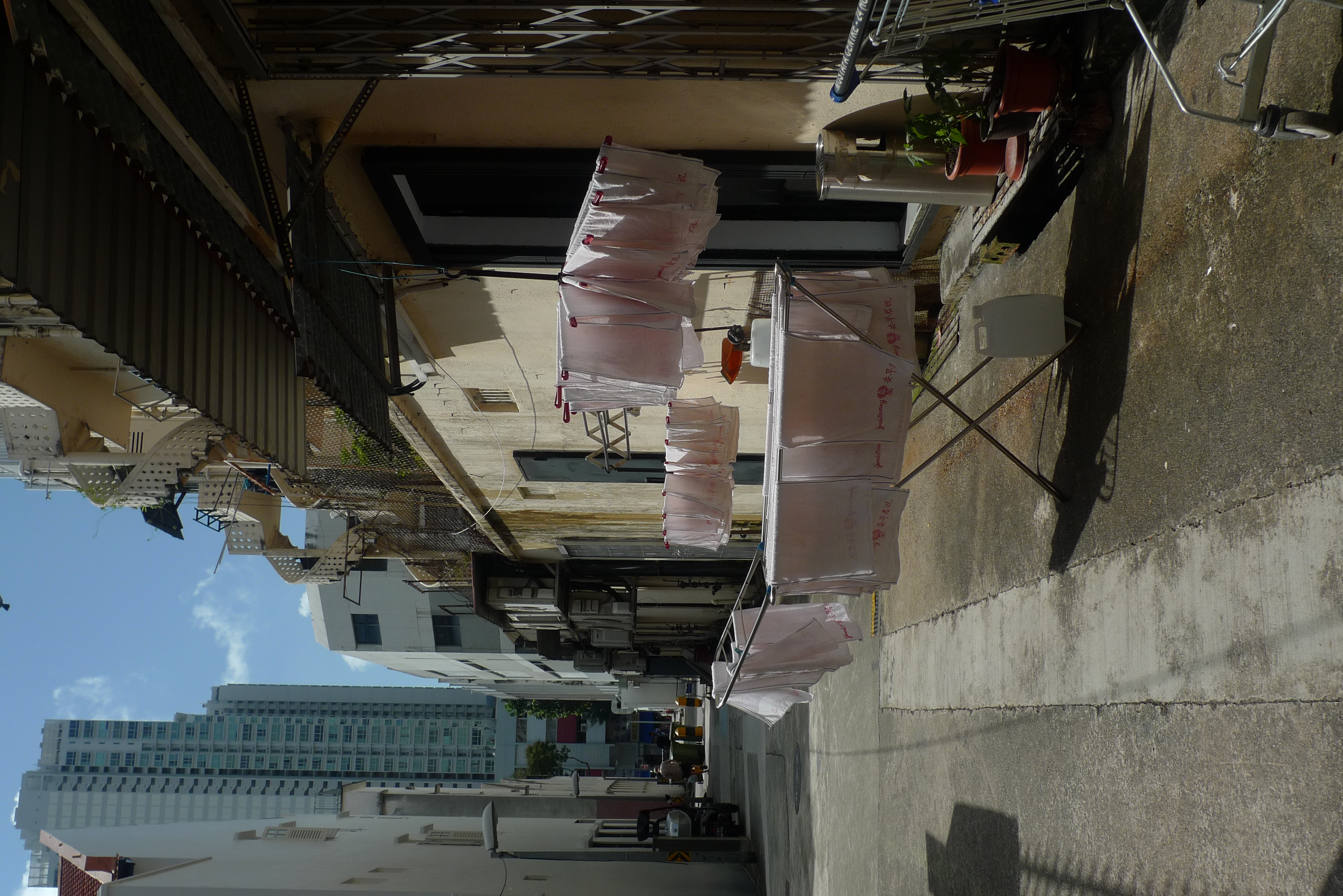 A set of clothes hangers placed alongside each other, each holding a number of Good Morning brand towels--white towels with Chinese print in red and script that says Good Morning, in a backstreet in Jalan Besar district, Singapore
