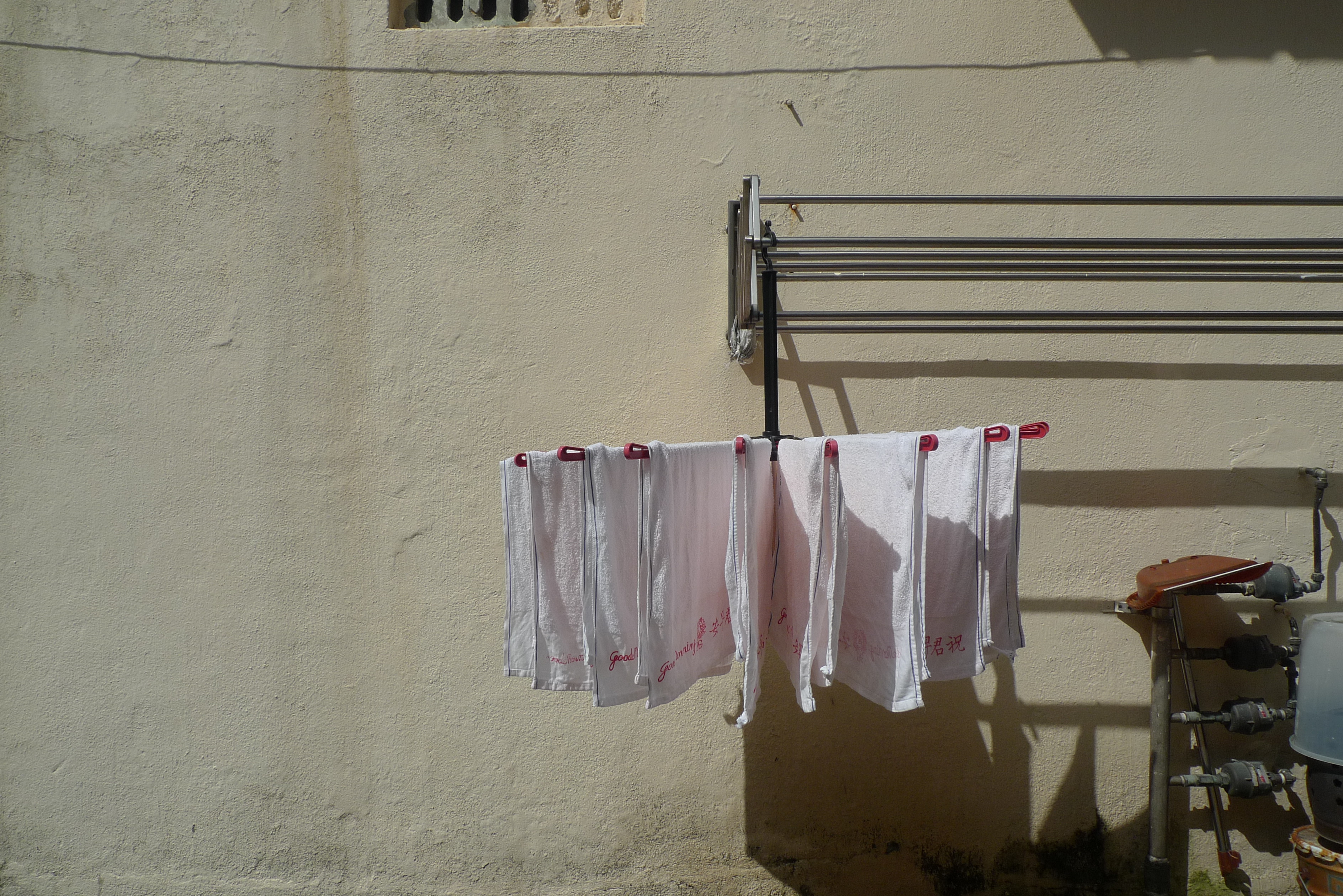 A clothes hanger number of Good Morning brand towels--white towels with Chinese print in red and script that says Good Morning, symmetrically placed, looking like a wide open flower, in a backstreet in Jalan Besar district, Singapore