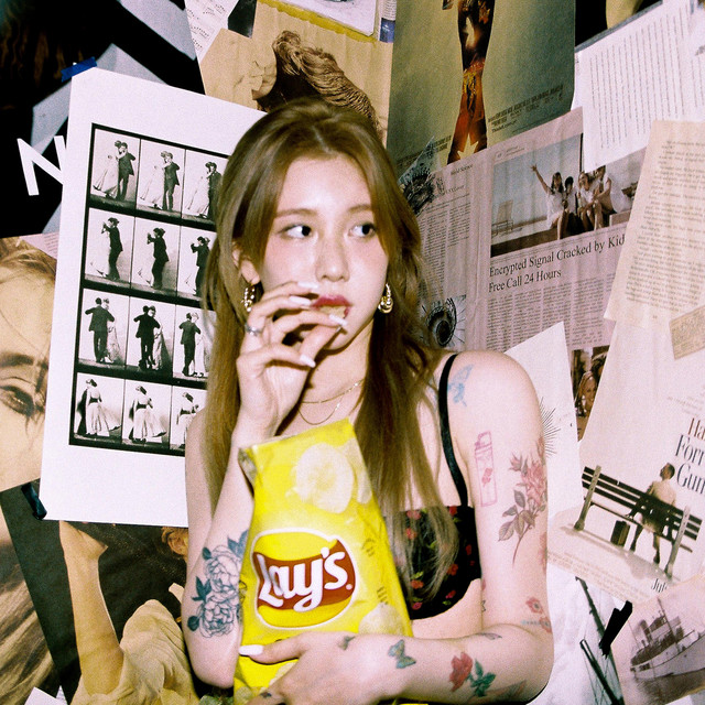Yerin eating a potato chip from a bag of Lay's against a background/wall with different posters