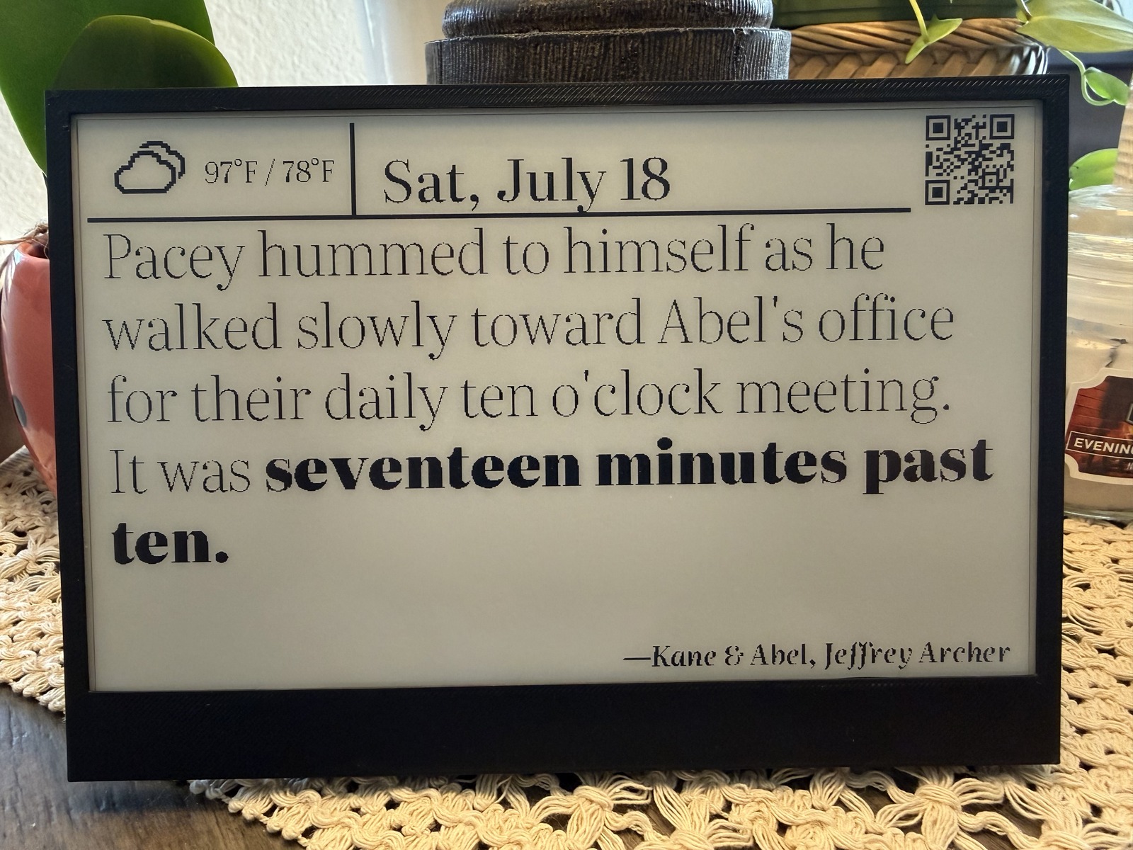 LitClock on a table, showing a passage from Kane & Abel at seventeen minutes past ten