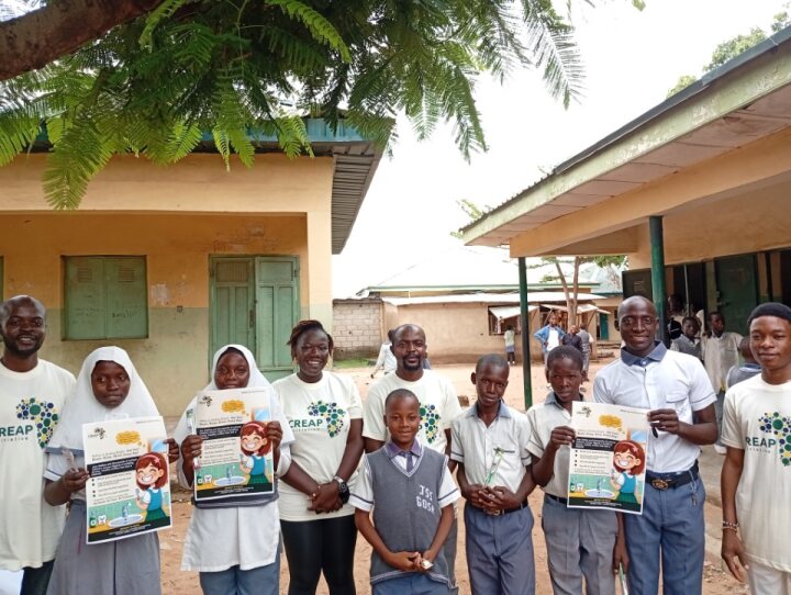 Learners hold up oral hygiene awareness flyers with the CREAP team