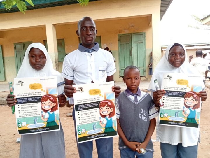 A pupil, teacher and CREAP staff member share the hygiene flyer