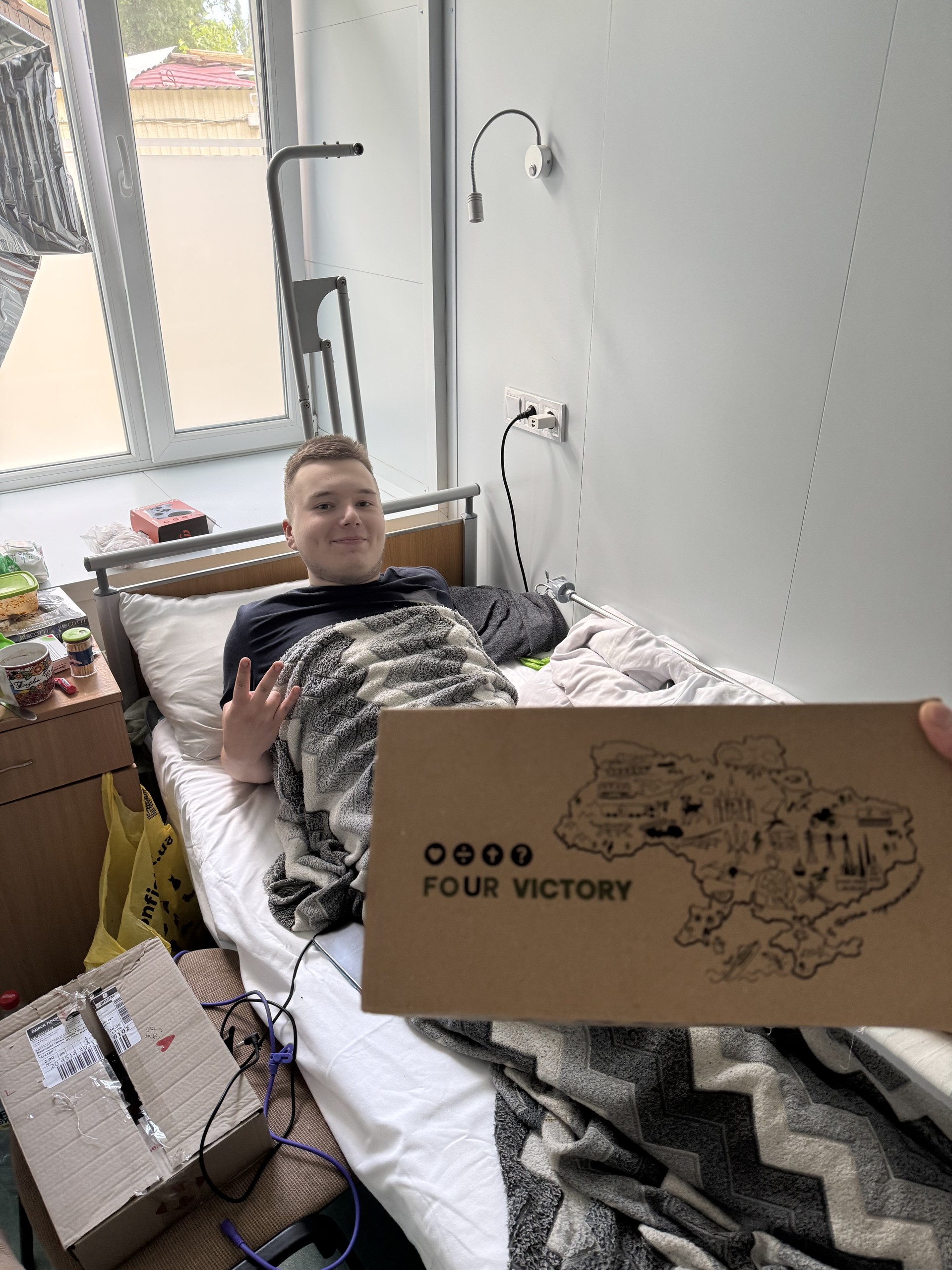 Danya in the hospital holding the "The Four" care package