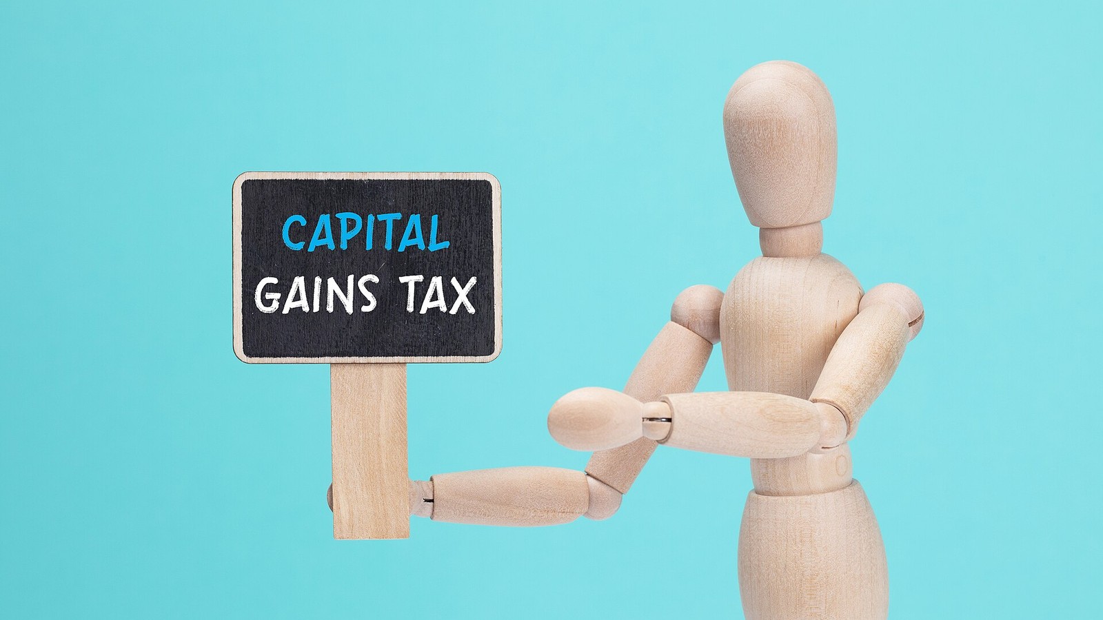 Illustrative photograph titled: The wooden doll holds a sign with the text CAPITAL GAINS TAX in his hands (53156508196)
