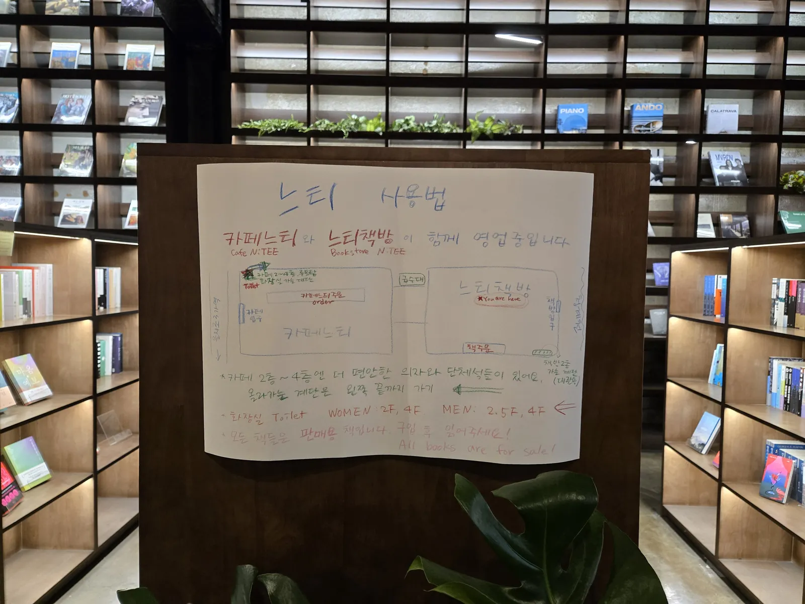 카페느티와 느티책방 이용법이 적힌 손글씨 안내판과 벽면 가득한 책장
