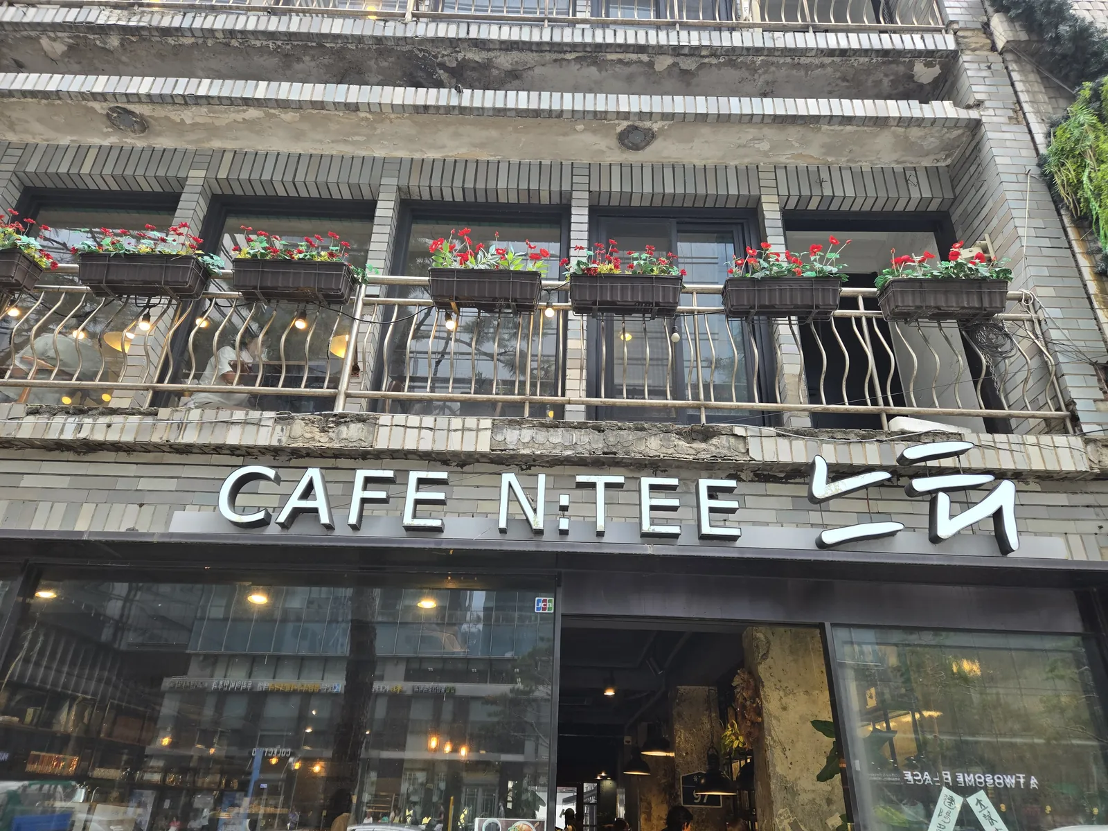 빨간 화분이 늘어선 창과 CAFE N:TEE 간판이 보이는 카페느티 외관