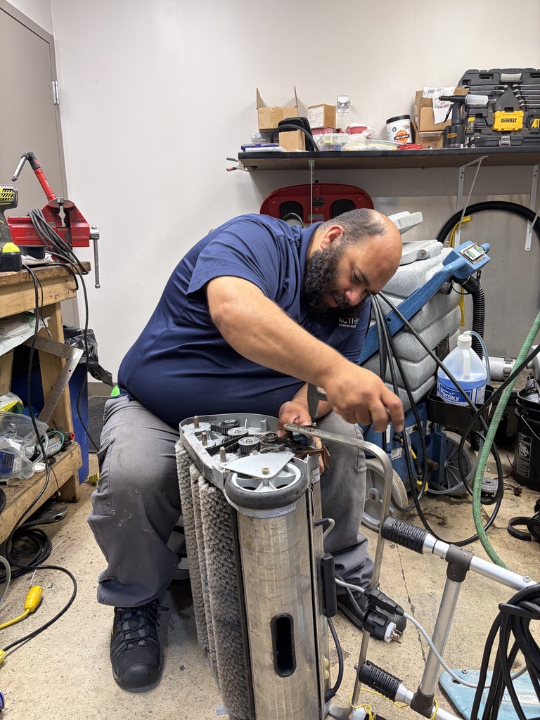 Action technician repairing floor-cleaning equipment