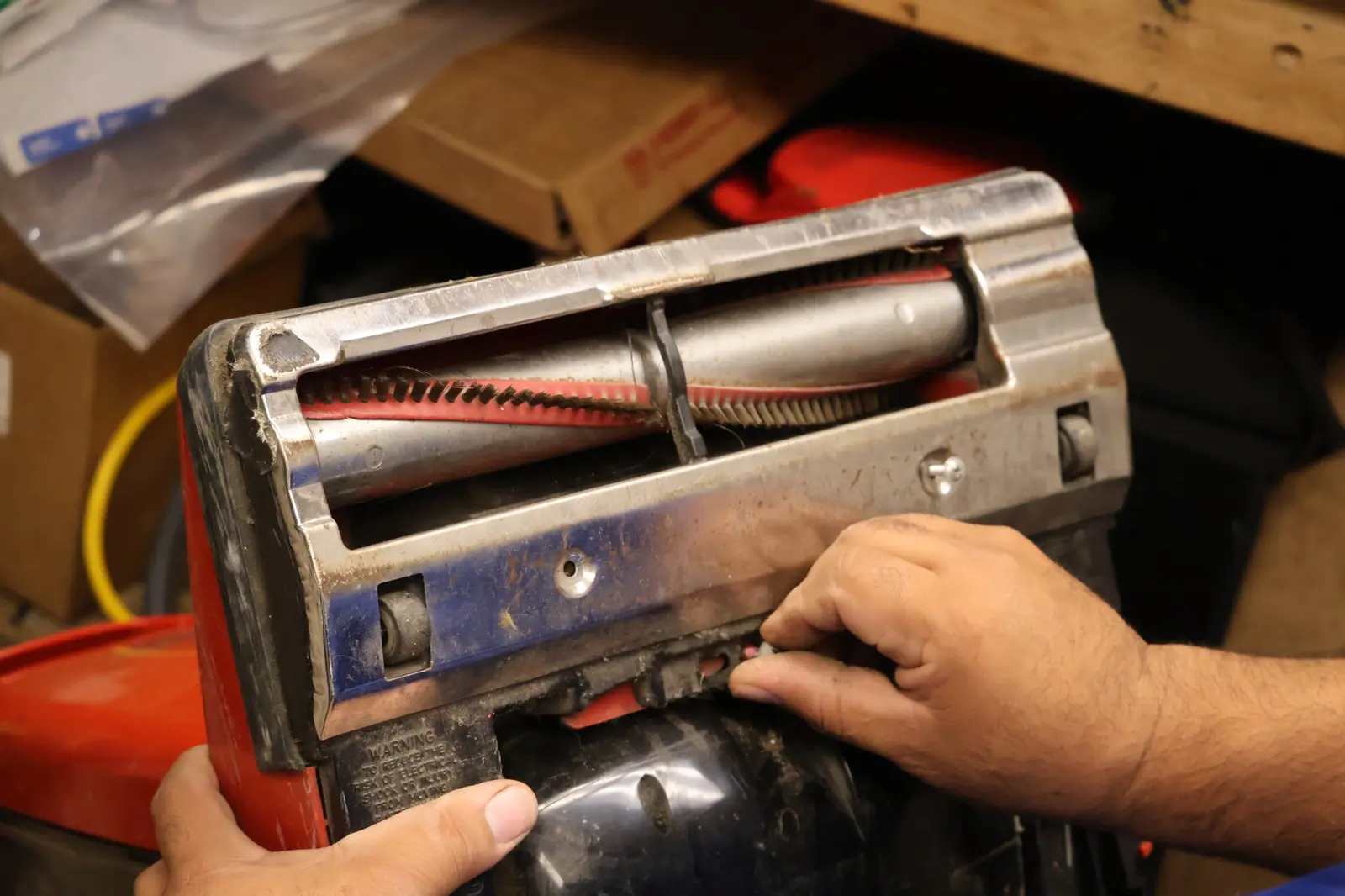 Close-up of hands repairing the brush assembly of commercial cleaning equipment