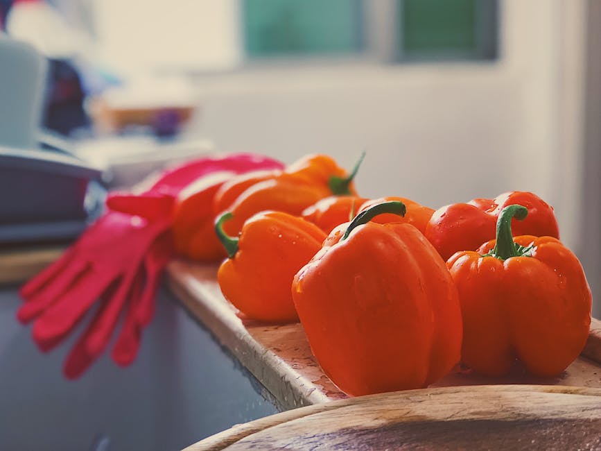 Bright orange bell peppers on a sunlit kitchen counter, perfect for cooking inspiration.