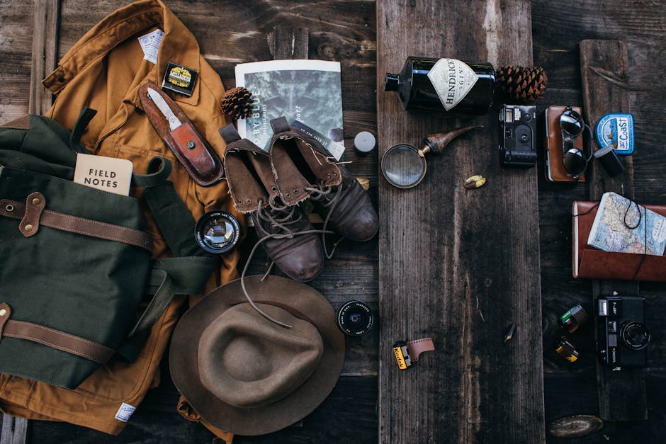 Top view of traveler clothing with hat and boots placed on wooden surface with old fashioned photo cameras and lenses