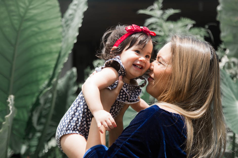 Mother and baby share a heartwarming moment in nature with bright sunlight and greenery.
