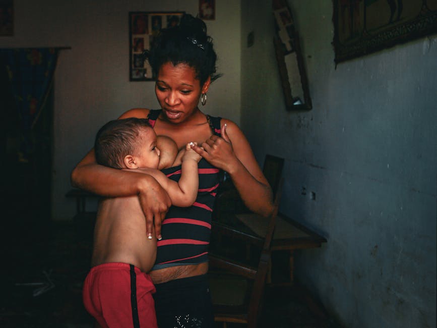 Mother tenderly breastfeeding her child in indoor setting, capturing a touching family moment.