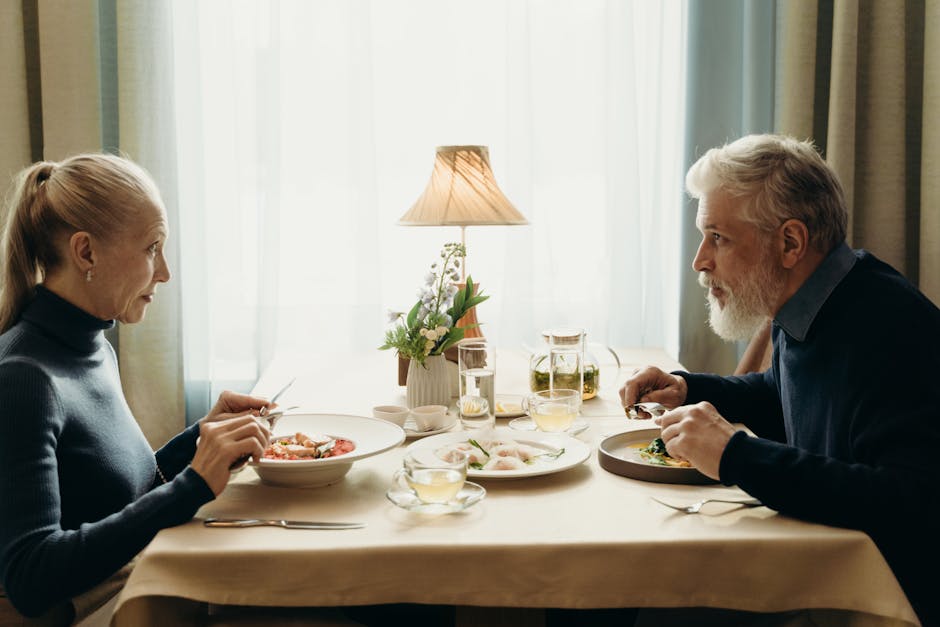 Elderly couple enjoying a meal together in a cozy, warmly lit indoor setting.