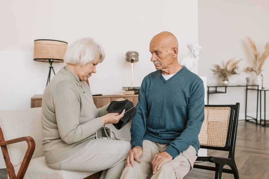 Elderly couple seated together, checking blood pressure with a sphygmomanometer indoors.
