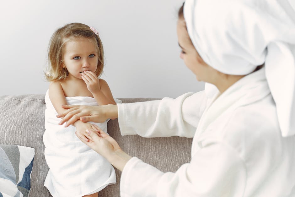 A mother gently interacts with her daughter wrapped in a towel, showcasing warmth and love.