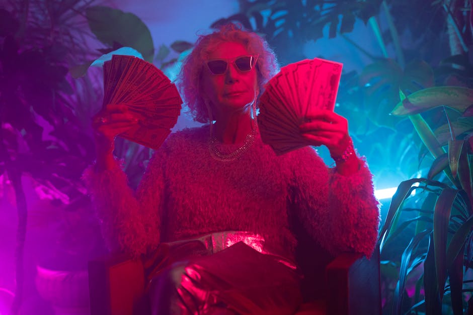 Senior woman with sunglasses holding cash in vibrant neon lighting, capturing a chic and confident lifestyle.