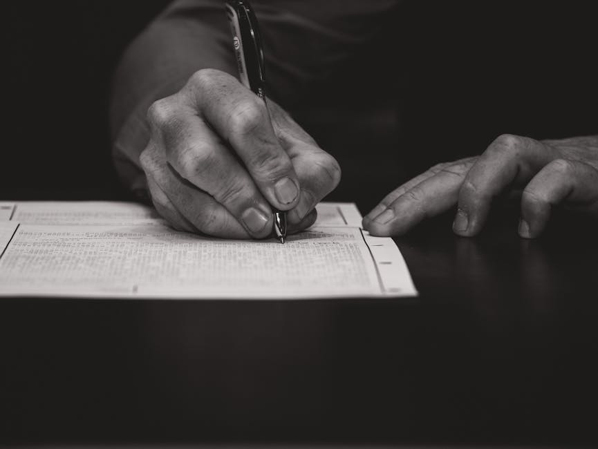 Monochrome image of a hand writing on a document, emphasizing attention to detail.