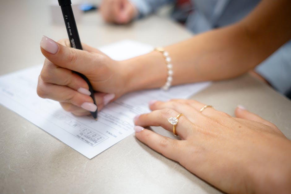 Detailed view of hands filling out a form with elegant jewelry and manicure.