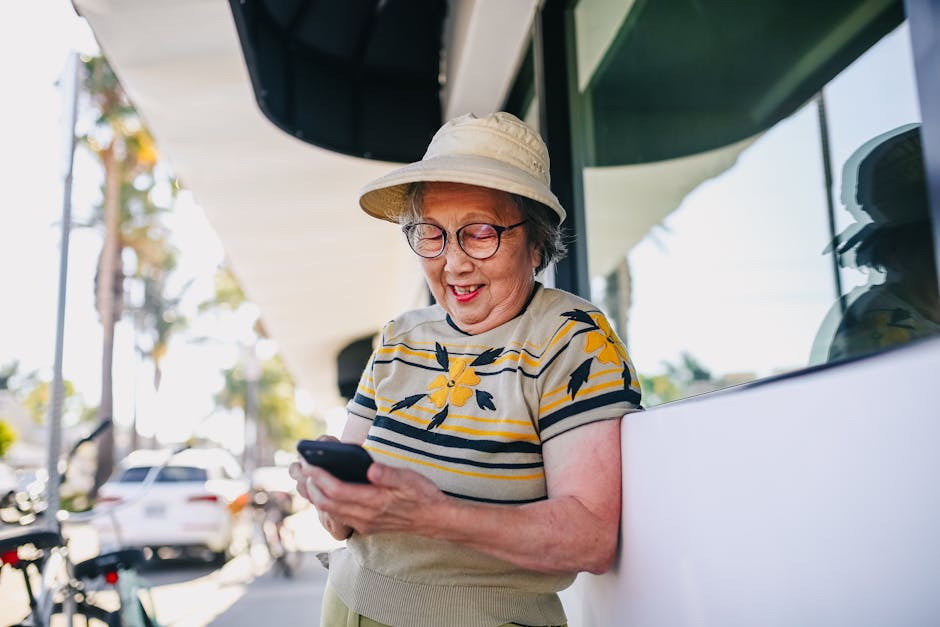 Smiling elderly woman using smartphone outdoors on a sunny day.